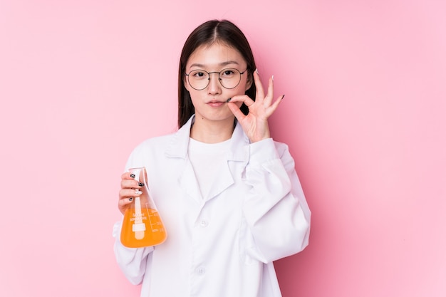 Giovane donna scientifica cinese con le dita sulle labbra mantenendo un segreto.