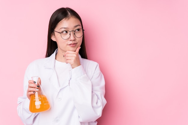Giovane donna scientifica cinese isolata guardando lateralmente con espressione dubbiosa e scettica.