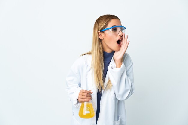 Giovane donna scientifica isolata sul muro bianco che grida con la bocca spalancata di lato