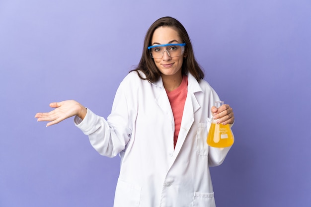 Giovane donna scientifica su sfondo isolato che ha dubbi mentre si alzano le mani