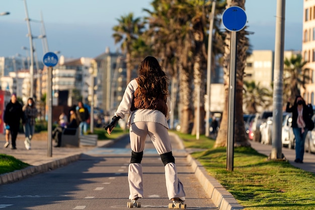 Giovane donna sconosciuta pattini a rotelle per la strada al tramonto nella vista posteriore di La Serena