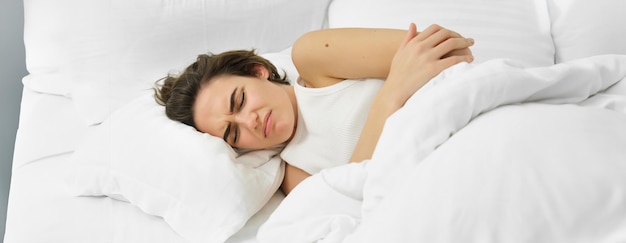 Giovane donna sdraiata a letto con mal di stomaco ha crampi dolorosi dolore mestruale