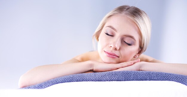 Giovane donna sdraiata su un lettino da massaggio che si rilassa con gli occhi chiusi salone spa donna