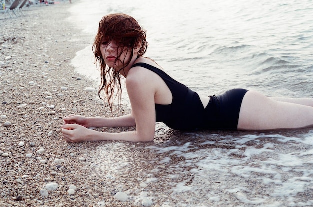 Giovane donna sdraiata sulla sabbia sulla spiaggia