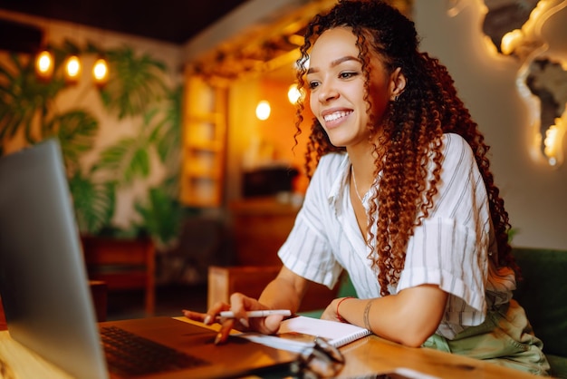 Giovane donna seduta al bar che fa shopping online utilizzando carta di credito e laptop Shopping online