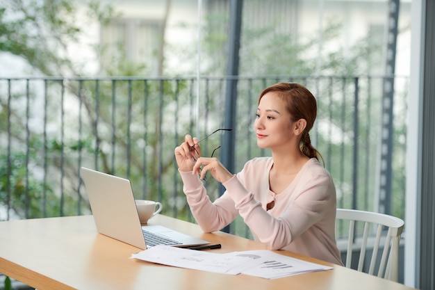 Giovane donna seduta al tavolo dell'ufficio con il computer portatile.