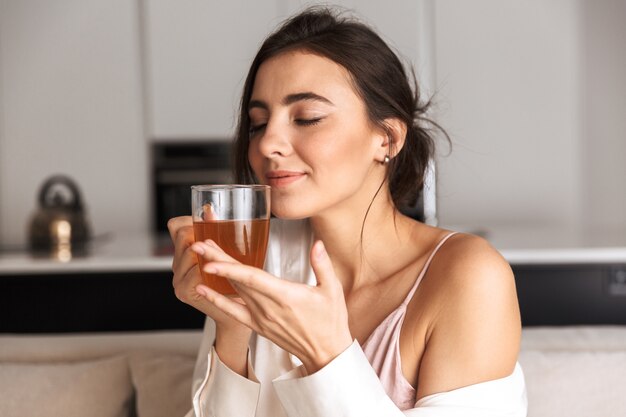 giovane donna seduta in cucina, tenendo il bicchiere con il tè