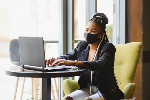 Giovane donna seduta in un caffè che lavora su un computer portatile