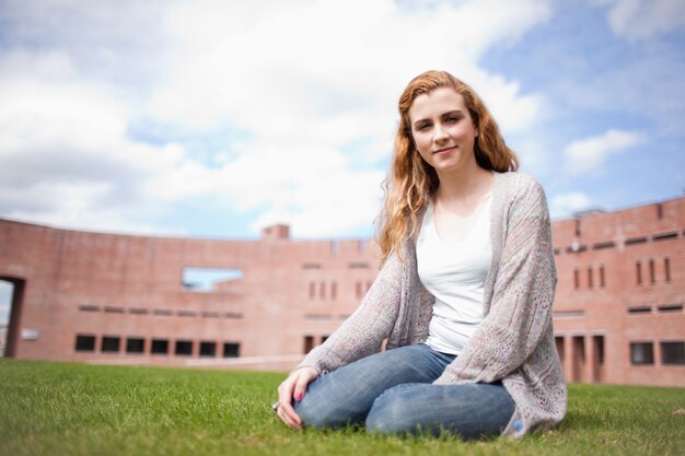 Giovane donna seduta su un prato fuori da un college