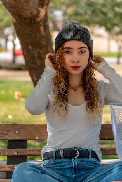 Giovane donna seduta su una panchina ad ammirare la vista in un bellissimo parco all'aperto