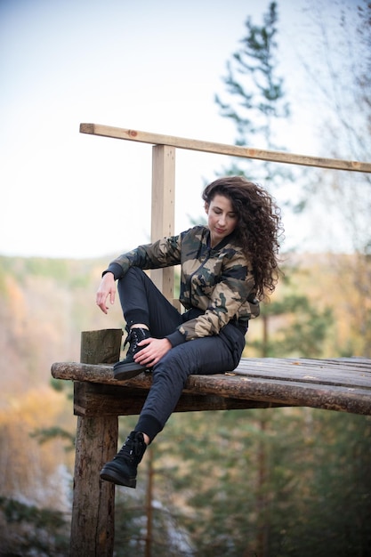 Giovane donna seduta su una piattaforma su uno sfondo di foresta sorridente che abbraccia una guida agghiacciante
