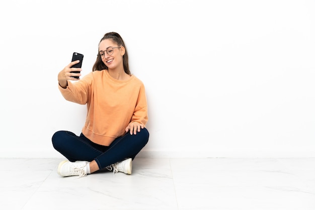 Giovane donna seduta sul pavimento facendo un selfie