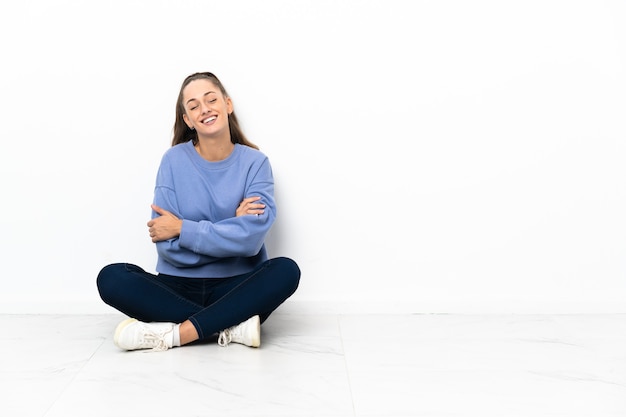 Giovane donna seduta sul pavimento felice e sorridente
