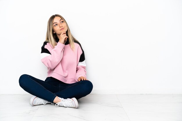 Giovane donna seduta sul pavimento in casa e guardando in alto