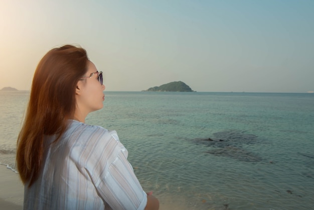 Giovane donna seduta sulla roccia sulla spiaggia