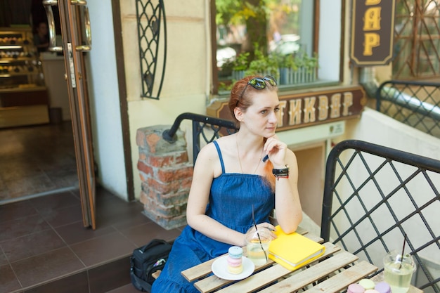giovane donna seduta sulla terrazza di un caffè che scrive i suoi piani