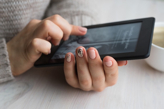 Giovane donna seduta vicino alla finestra con un e-book