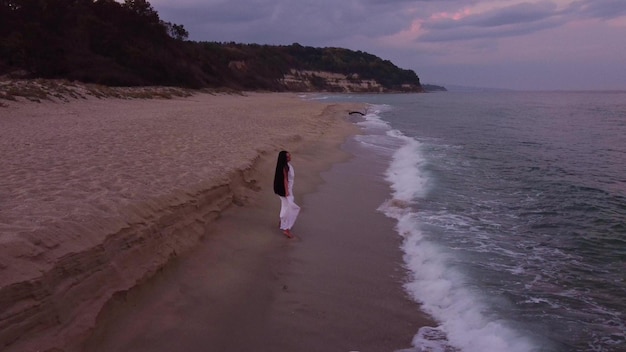 Giovane donna sensuale felice che corre sulla spiaggia la sera