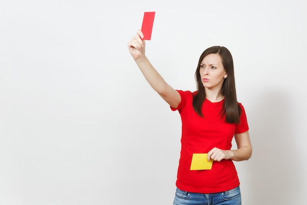 Giovane donna seria europea, arbitro di calcio tenere scegliere carte da calcio gialle e rosse, proporre il ritiro del giocatore dal campo isolato su sfondo bianco. Sport, gioco, concetto di stile di vita sano.