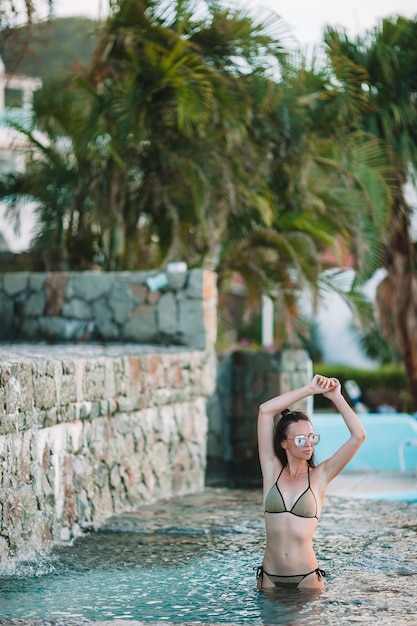 Giovane donna sexy che gode del resto sul bordo della piscina all'aperto