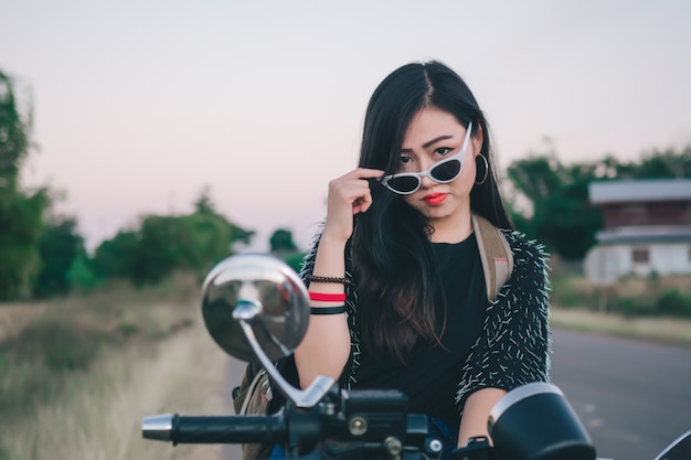 Giovane donna sexy su una moto in natura sul tramonto. Concetto di viaggio