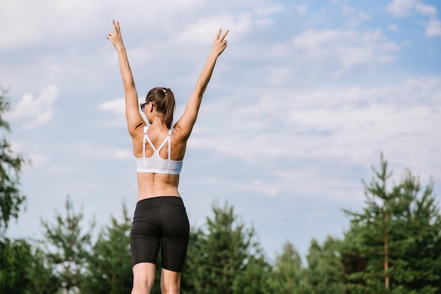 Giovane donna slim fit che fa esercizio sportivo all'aperto nel parco alla giornata di sole