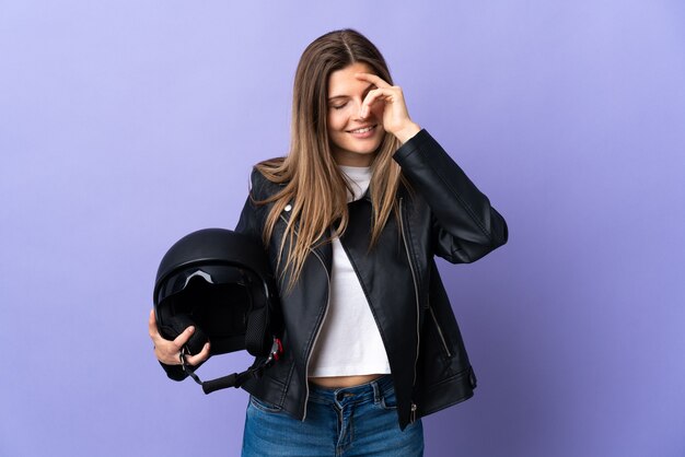 Giovane donna slovacca che tiene un casco da motociclista isolato su sfondo viola ridendo