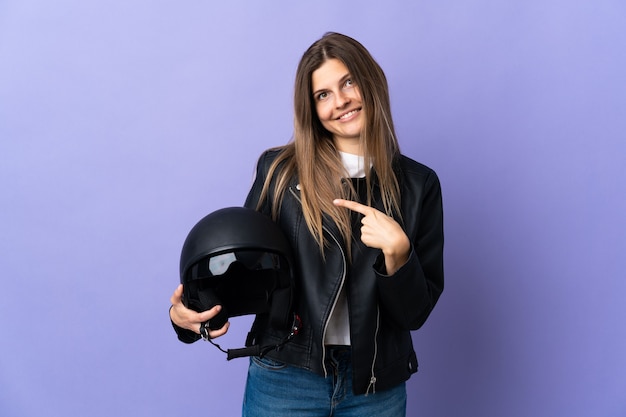 Giovane donna slovacca che tiene un casco da motociclista isolato su viola rivolto indietro