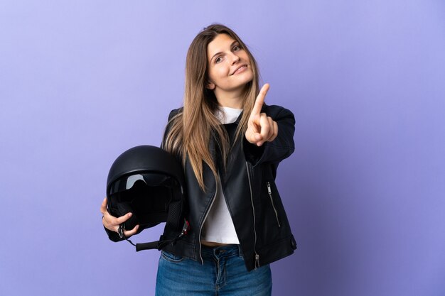 Giovane donna slovacca che tiene un casco del motociclo isolato su sfondo viola che mostra e alza un dito