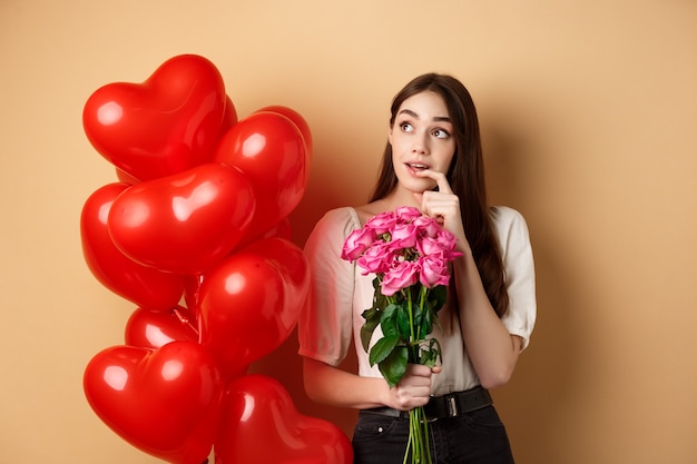 Giovane donna sognante che tiene in mano un mazzo di rose e pensa all'ammiratore segreto il giorno di San Valentino...