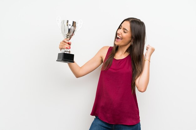 Giovane donna sopra bianco isolato che tiene un trofeo