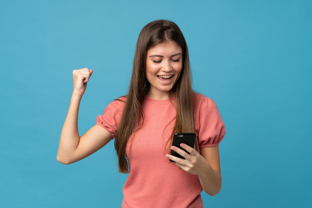 Giovane donna sopra blu isolato utilizzando il telefono cellulare