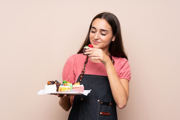 Giovane donna sopra isolata che tiene le mini torte