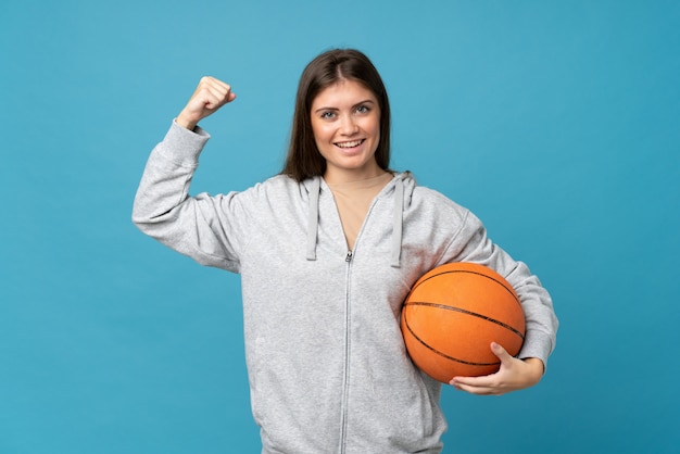 Giovane donna sopra isolata con la palla di pallacanestro