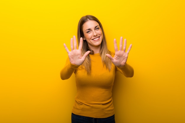 Giovane donna sopra su giallo contando dieci con le dita