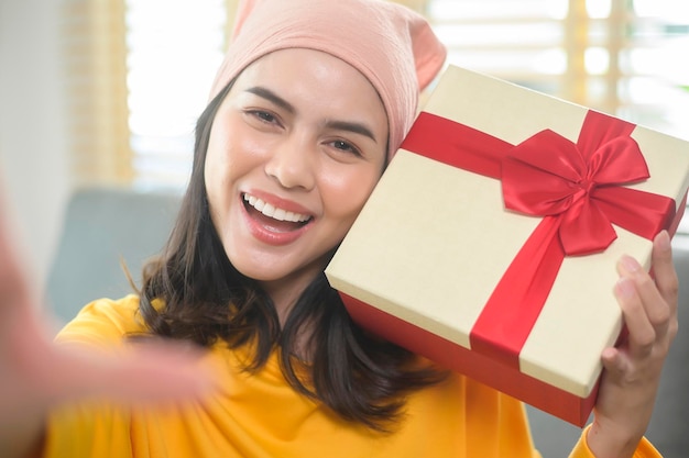 Giovane donna sorpresa che apre una confezione regalo in soggiorno