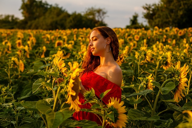 Giovane donna sorridente al tramonto in un campo di girasoli