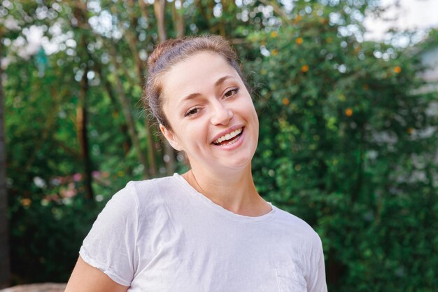 Giovane donna sorridente all'aperto bella ragazza bruna che riposa sul parco o giardino sfondo verde h...