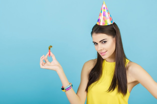 Giovane donna sorridente attraente con un cappello di compleanno