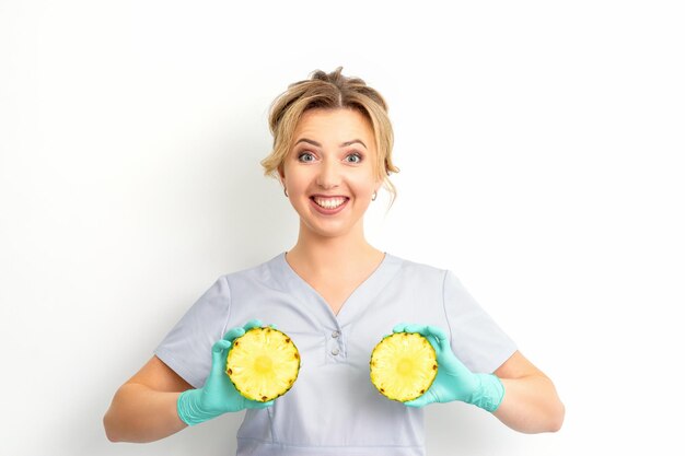 Giovane donna sorridente caucasica medico nutrizionista azienda fette di ananas su sfondo bianco isolato concetto di salute del seno