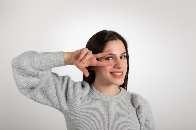 Giovane donna sorridente che fa la V per il gesto di vittoria con le dita Simbolo di successo