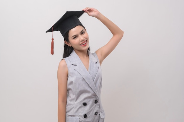 Giovane donna sorridente che indossa l'educazione e l'università del cappello di laurea