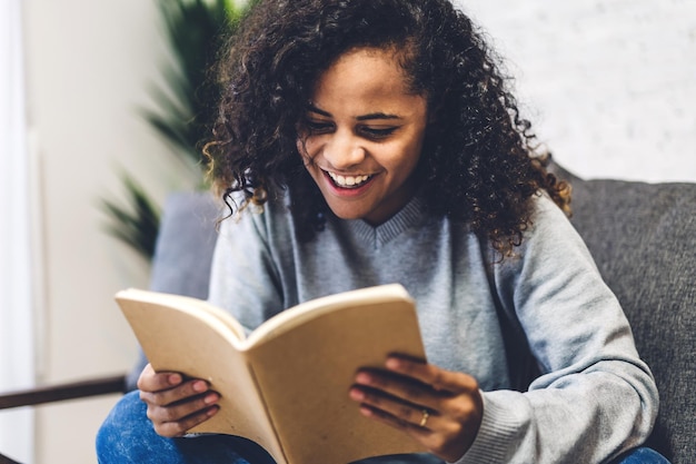 Giovane donna sorridente che legge un libro mentre è seduta sul sedile
