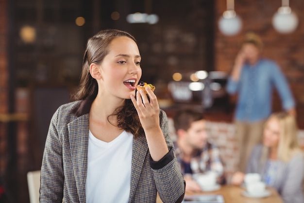 Giovane donna sorridente che mangia muffin