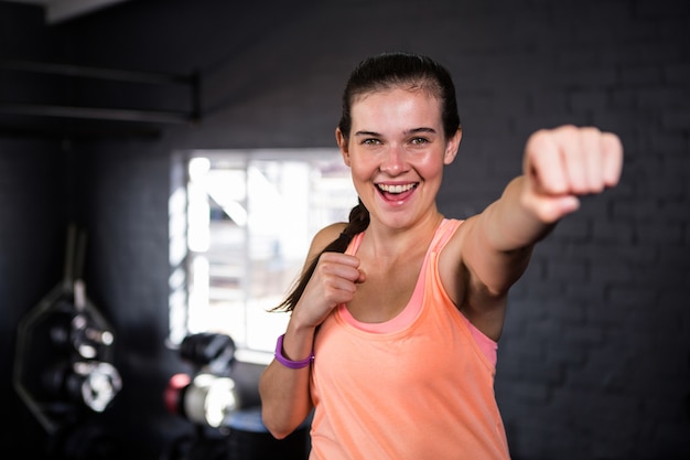 Giovane donna sorridente che perfora in palestra