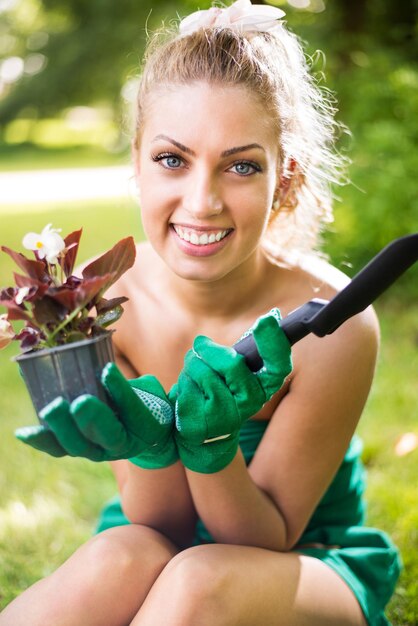 Giovane donna sorridente che pianta fiori in giardino.