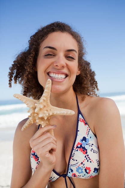 Giovane donna sorridente che tiene fiero una stella marina