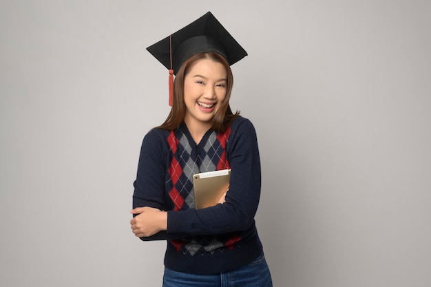 Giovane donna sorridente che tiene il cappello di laurea per l'istruzione e l'università conceptx9