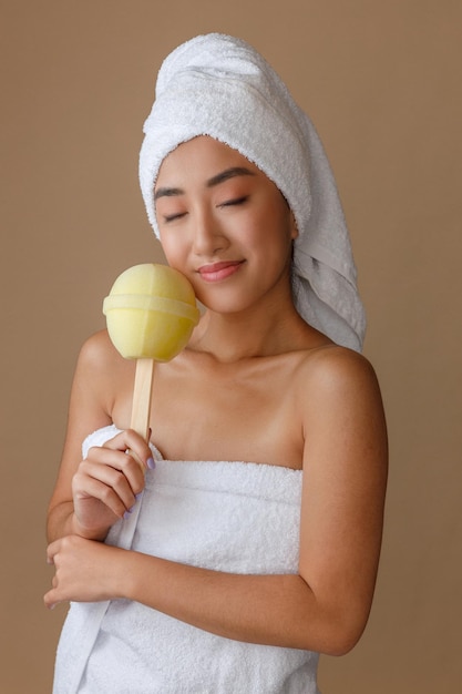 Giovane donna sorridente che tiene spugna da bagno lecca-lecca