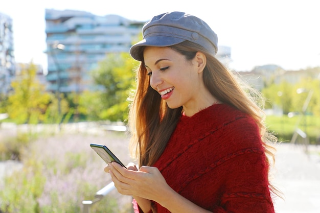 Giovane donna sorridente che usa il cellulare mentre si trova in città